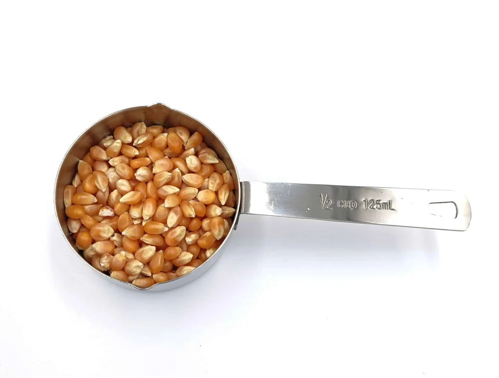 Edelstahl-Messbecher mit 125 ml Volumen, gefüllt mit Popcornmais, ideal für kleinere Portionen.