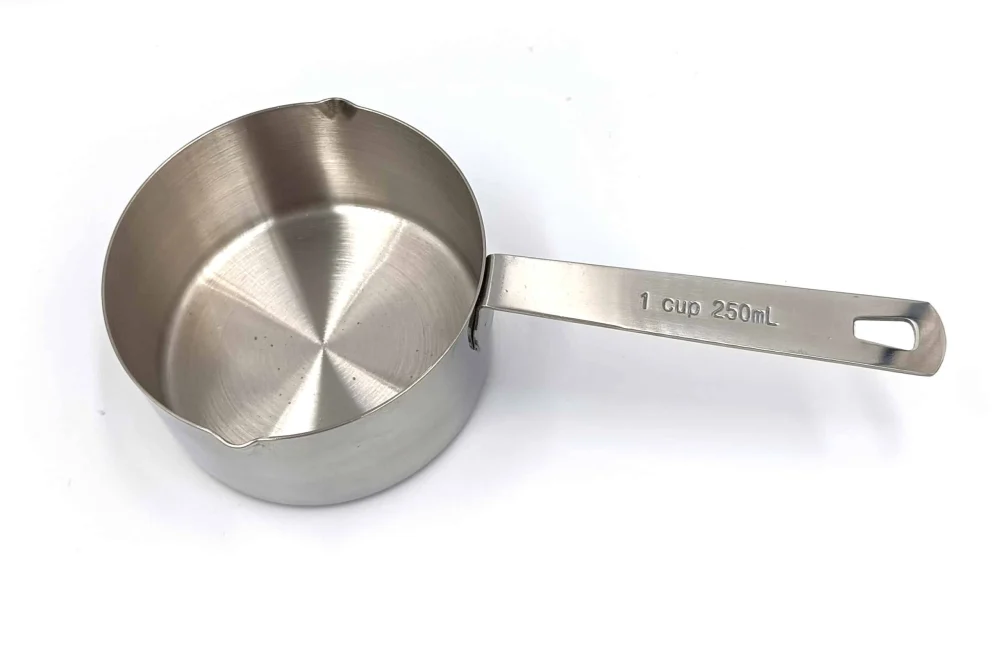 Edelstahl-Messbecher mit 250 ml Füllvolumen, gefüllt mit Popcornmais, auf weißem Hintergrund.